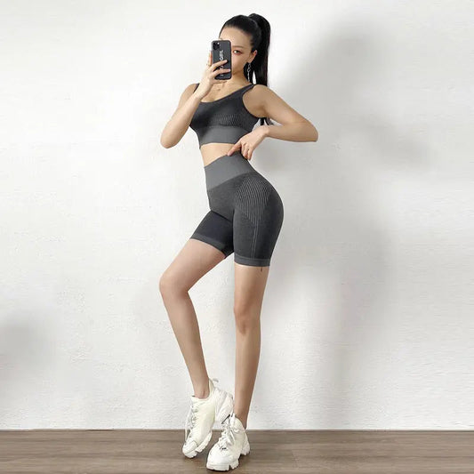 Slim fit women's yoga fitness shorts set in gray nylon and spandex, modeled with matching sports bra and white sneakers.